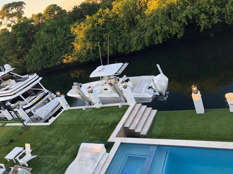 Slide: The Image of 2021 Boston Whaler Dauntless 27 docked by a luxurious waterfront property with a pool. - 3