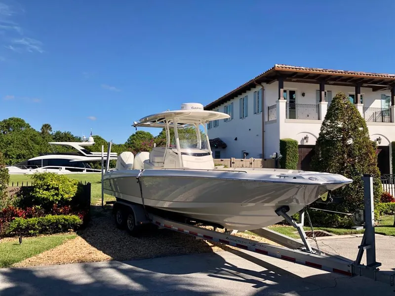 Slide: The Image of 2021 Boston Whaler Dauntless 27 boat on trailer in front of a luxury house. - 6