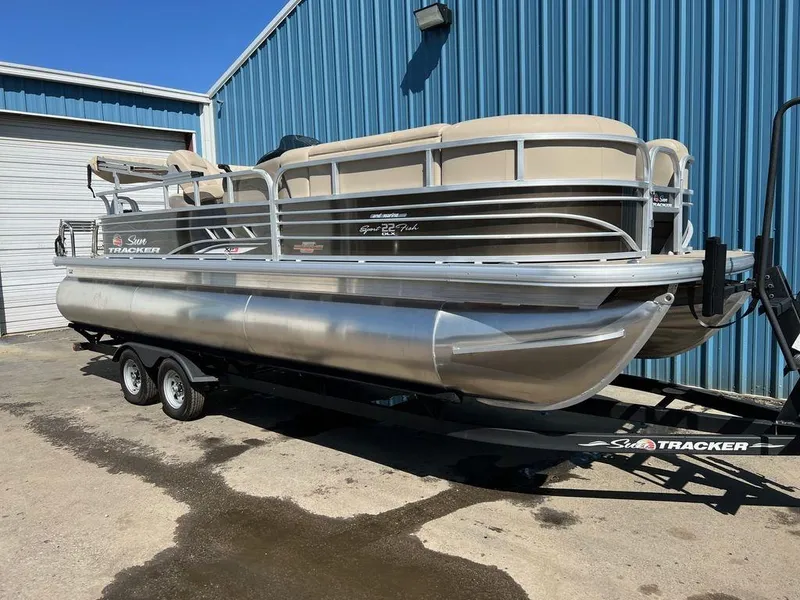 Slide: The Image of 2023 Sun Tracker SportFish™ 22 XP3 pontoon boat on trailer, parked outside blue building. - 3