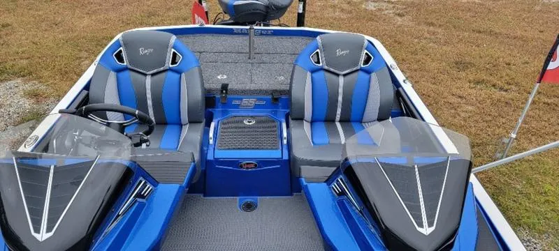Slide: The Image of 2023 Ranger Z 521 RC boat with blue and gray seating, parked on grass. - 13