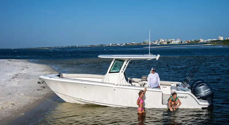 Slide: The Image of 2023 Sailfish 272 CC boat docked on a sandy shore with people enjoying the water. - 1