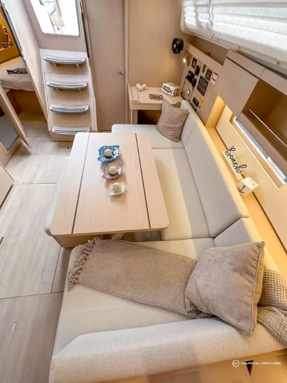 Slide: The Image of 2024 Beneteau Oceanis 40.1 interior, cozy seating area with table and decor. - 12