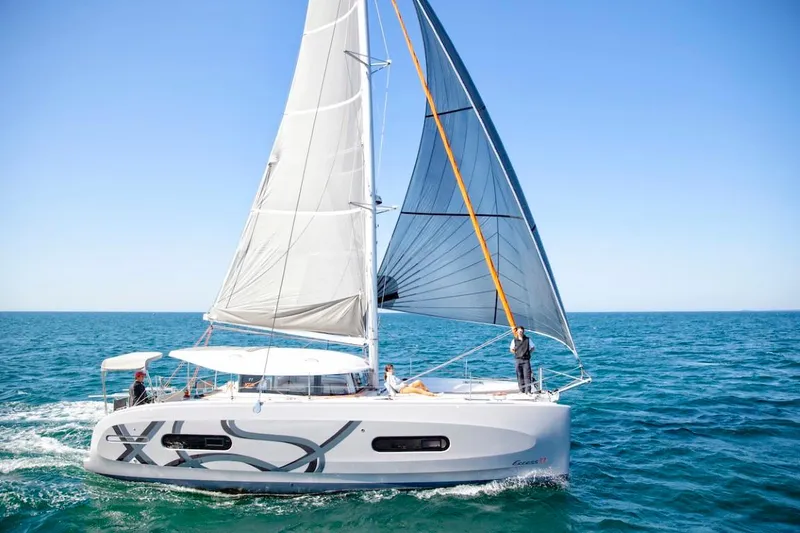 Slide: The Image of 2024 Excess 11 sailboat cruising on open water under clear blue sky. - 1