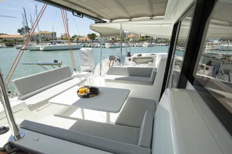 Slide: The Image of 2024 Excess 11 yacht with spacious outdoor seating and dining area in a marina. - 17