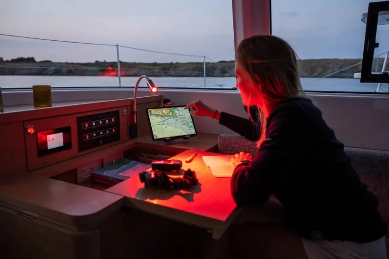Slide: The Image of Woman navigating on Excess 14 sailboat, 2024 model, using a tablet and red light. - 3
