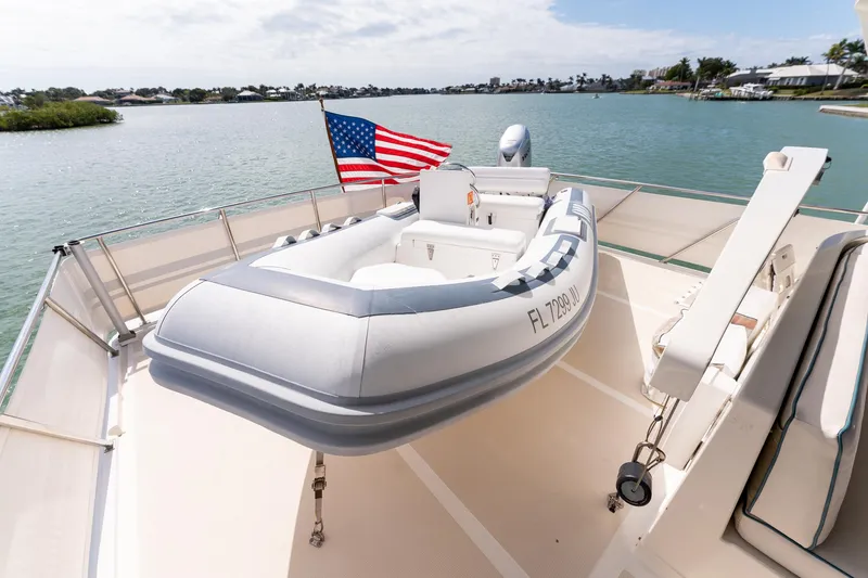 Slide: The Image of 1998 Offshore Yachts 54 Pilot House with inflatable boat on deck, American flag, scenic water view. - 35