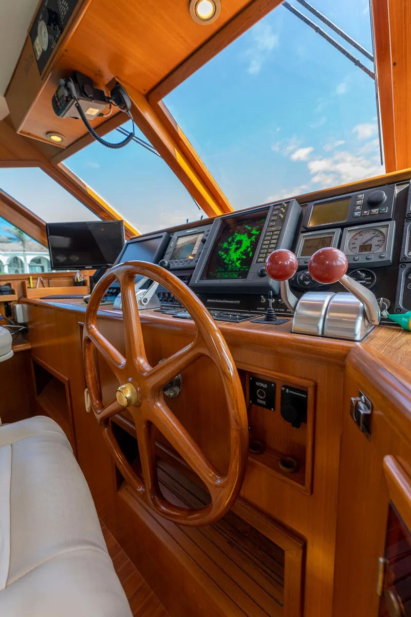 Slide: The Image of 1998 Offshore Yachts 54 Pilot House helm with wooden steering wheel and advanced navigation systems. - 40