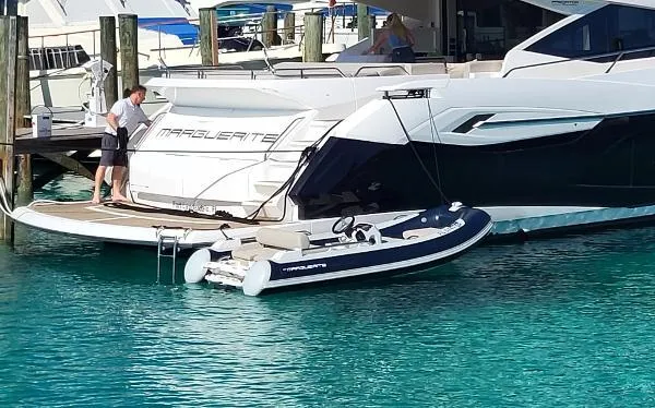 Slide: The Image of Sunseeker Predator 74 XPS 2020 yacht docked with a small inflatable boat in clear water. - 3