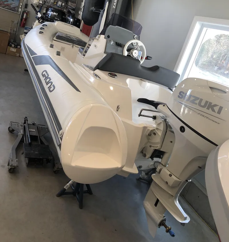 Slide: The Image of 2023 Grand G 420 inflatable boat with Suzuki outboard motor in a garage. - 2