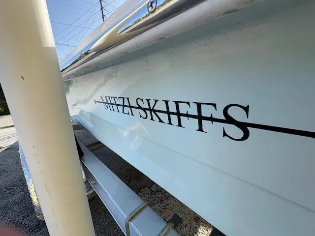 Slide: The Image of 2025 Mitzi Skiffs 17 boat on trailer, side view with logo visible. - 10