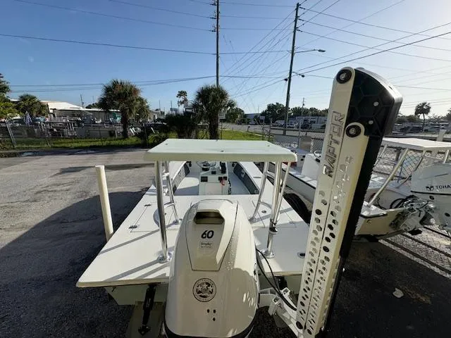 Slide: The Image of 2025 Mitzi Skiffs 17 boat with outboard motor, parked outdoors on a sunny day. - 6