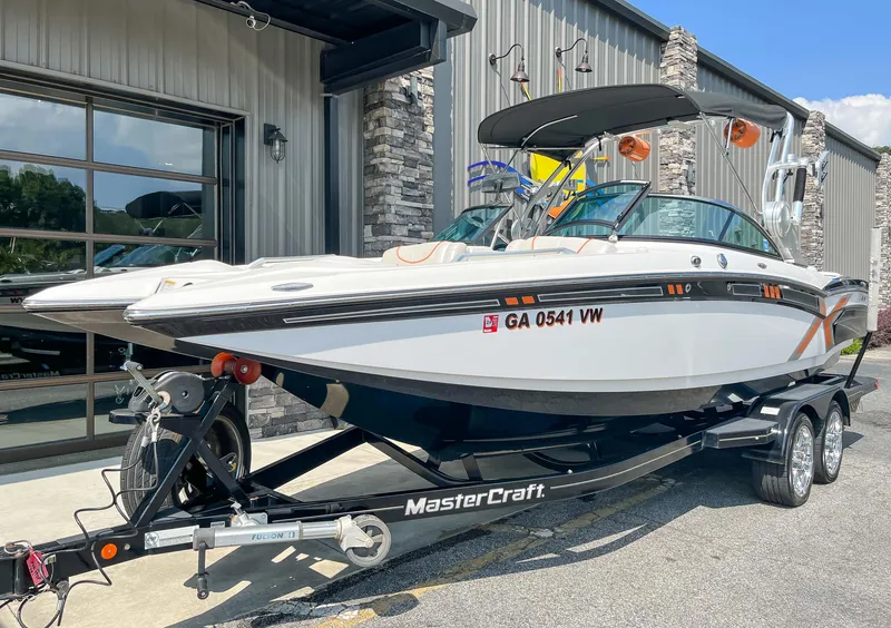 Slide: The Image of 2013 MasterCraft XStar boat on a trailer outside a building. - 2