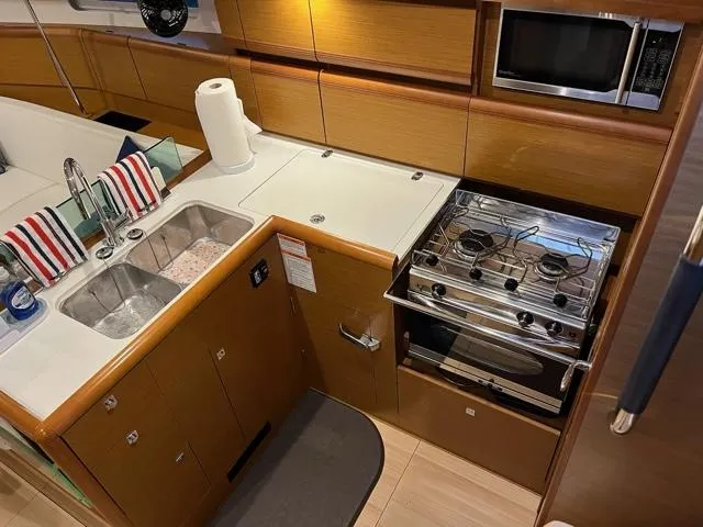 Slide: The Image of Modern kitchen in 2019 Jeanneau Sun Odyssey 389 yacht with stove, sink, and microwave. - 15