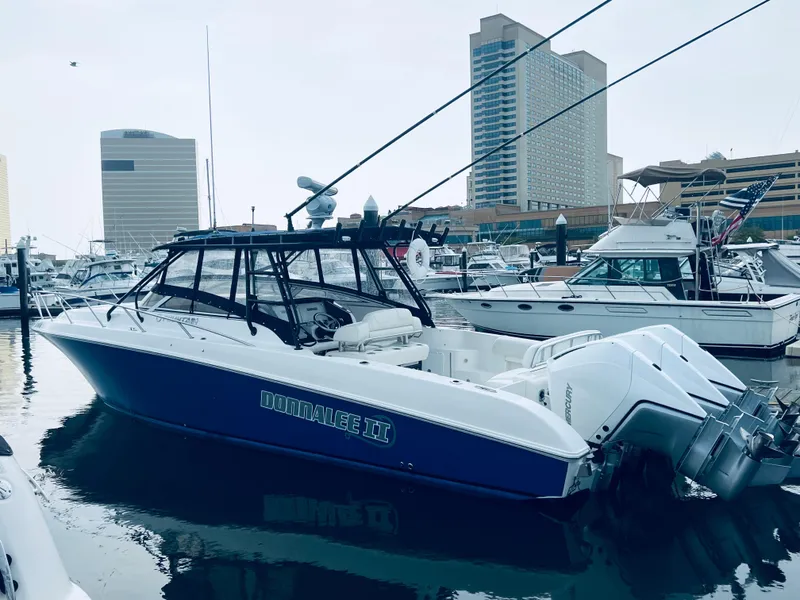 The Image of 2004 Fountain 38 LX boat docked in a marina with cityscape background. - 0