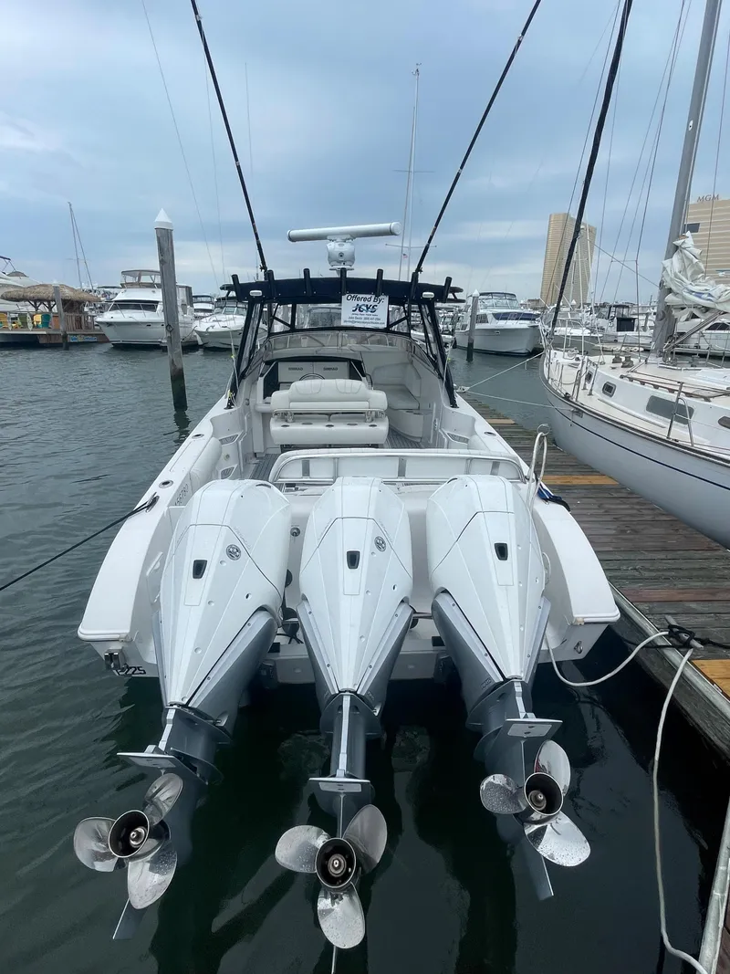 Slide: The Image of 2004 Fountain 38 LX boat with triple outboard engines docked at a marina. - 22