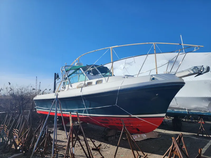 Slide: The Image of 2005 Albin 28 boat on stands, blue hull, red bottom, clear sky background. - 2