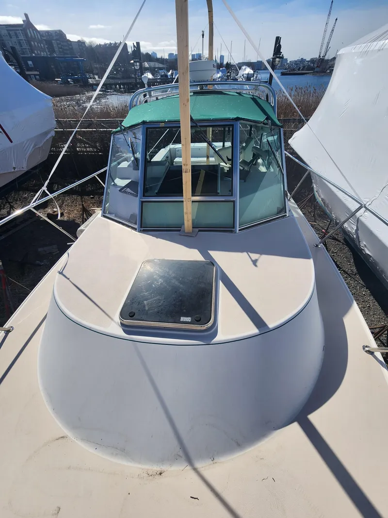 Slide: The Image of 2005 Albin 28 boat with green canopy, docked and covered, viewed from the bow. - 5