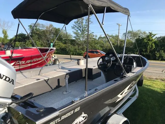 Slide: The Image of 2023 Polar Kraft Outlander 165 SC boat with canopy, parked on grass. - 0