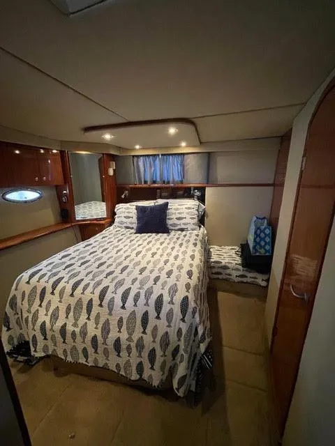 Slide: The Image of 2006 Cruisers Yachts 385 Motoryacht bedroom with bed, wooden cabinets, and ambient lighting. - 12