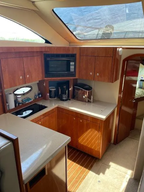 Slide: The Image of 2006 Cruisers Yachts 385 Motoryacht kitchen with wood cabinetry, microwave, and countertop appliances. - 5