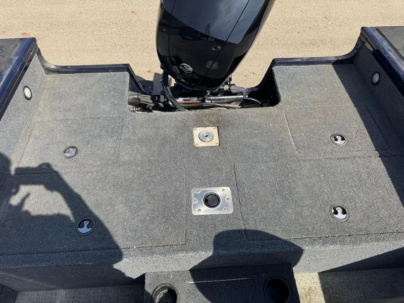 Slide: The Image of 2023 Tracker Targa V-18 WT boat deck with motor, featuring gray carpeting and mounting points. - 9