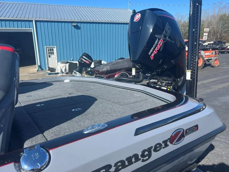 Slide: The Image of 2023 Ranger Z521R Cup Anniversary boat with Mercury engine, docked near a blue building. - 2