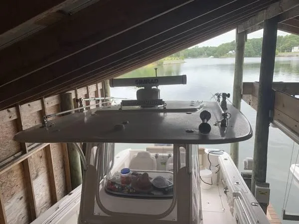 Slide: The Image of 2016 Robalo R300 Center Console boat docked under a wooden shelter by a lake. - 24