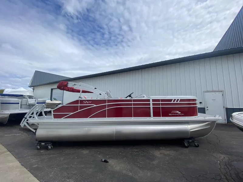 The Image of 2023 Bennington 21 SXSB pontoon boat in red and silver, docked outside a warehouse. - 0