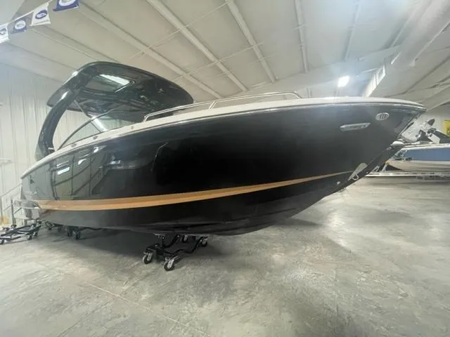 Slide: The Image of 2024 Chaparral 287 SSX boat in showroom, black hull with gold stripe. - 3