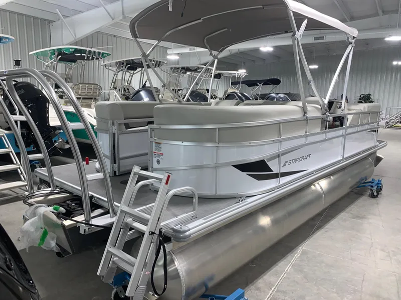 Slide: The Image of 2024 Starcraft LX22 R pontoon boat in showroom, side view. - 1