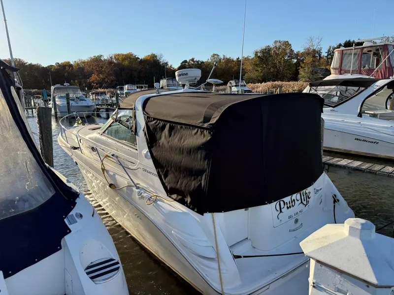 Slide: The Image of 1998 Sea Ray 330 Sundancer docked at marina, covered with black canvas, surrounded by other boats. - 16