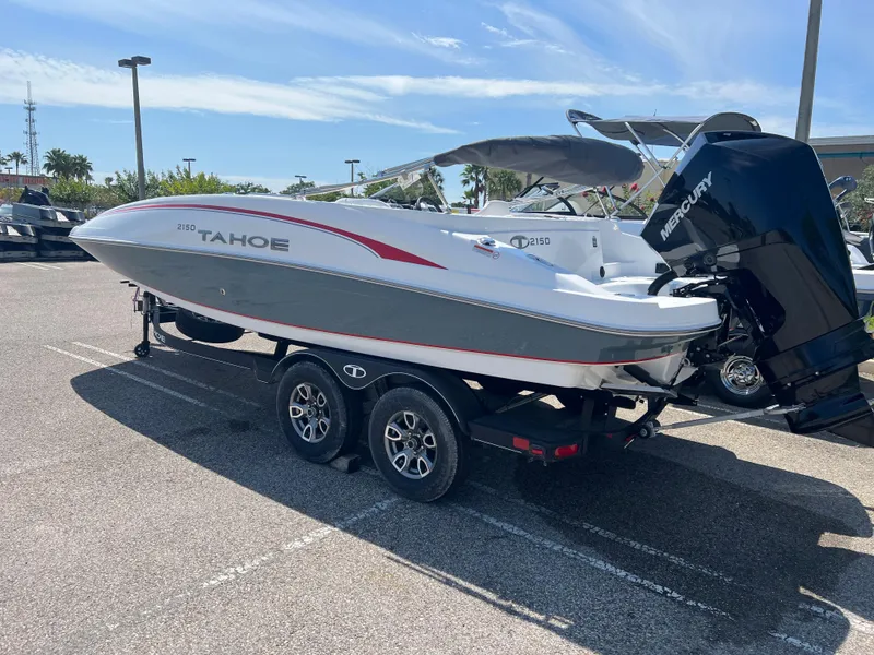 Slide: The Image of 2023 Tahoe 2150 boat on trailer in parking lot, featuring Mercury outboard motor. - 2