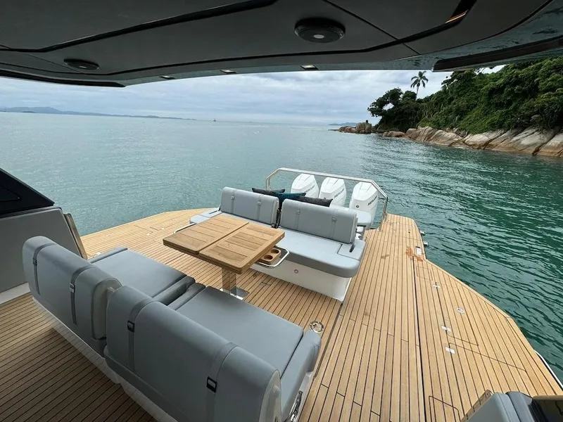 Slide: The Image of Luxury Schaefer V44 yacht deck with seating and table, overlooking serene ocean and lush coastline. - 15
