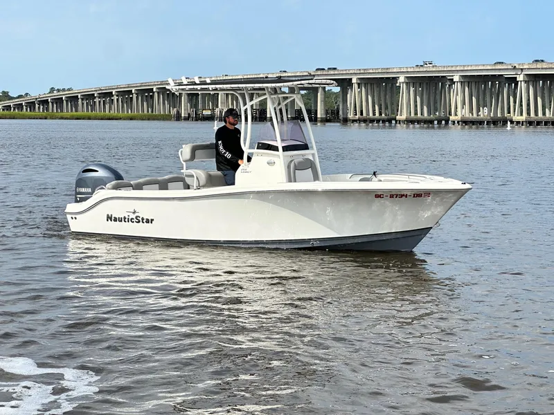 Slide: The Image of 2021 NauticStar 2102 Legacy boat on water near a bridge. - 0