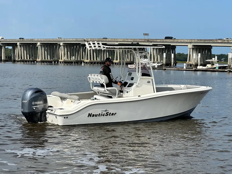 Slide: The Image of 2021 NauticStar 2102 Legacy boat on water with bridge in background. - 1