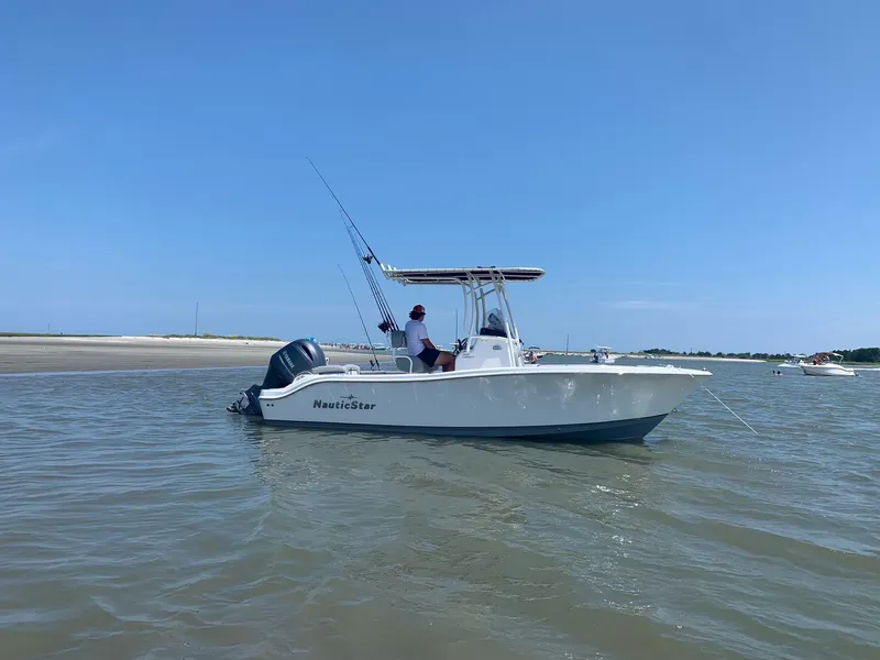 Slide: The Image of 2021 NauticStar 2102 Legacy boat on calm water, clear blue sky. - 5