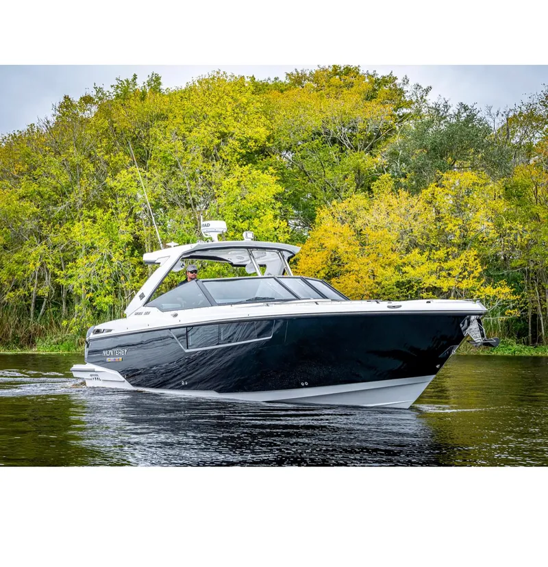 Slide: The Image of 2022 Monterey 38 Super Sport boat cruising on a river with lush green trees. - 2