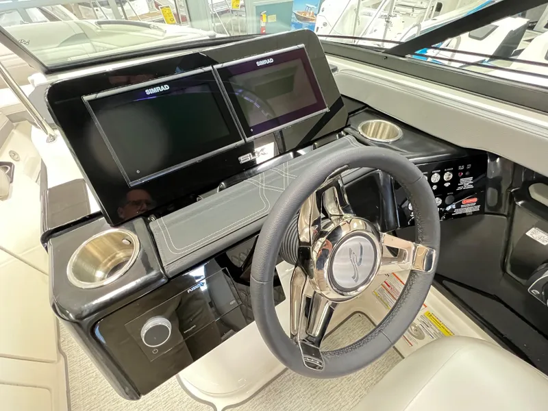 Slide: The Image of 2023 Sea Ray SLX 260 helm with dual Simrad displays and modern steering wheel. - 8