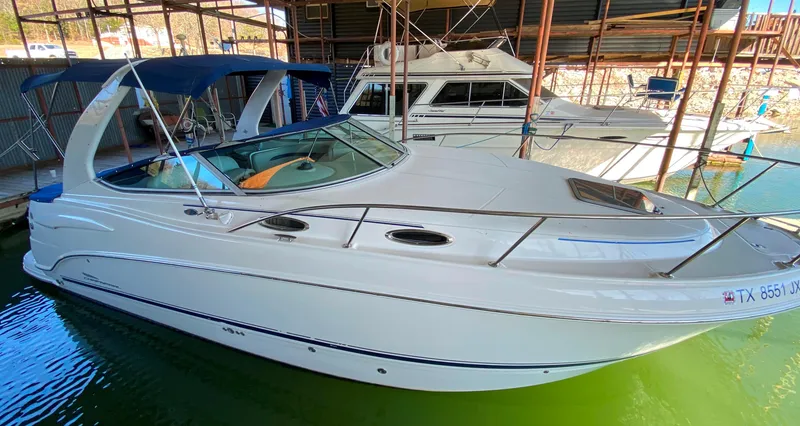 Slide: The Image of 2003 Chaparral 280 Signature boat docked in marina, featuring sleek design and blue canopy. - 2