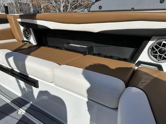 Slide: The Image of 2023 Axis Wake Research A225 boat interior with tan and white seating, cup holders, and speakers. - 5