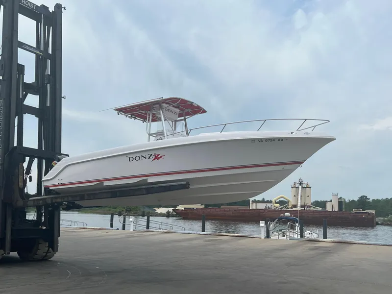 Slide: The Image of 2002 Donzi 29 ZF Cuddy boat lifted by forklift near waterfront. - 1