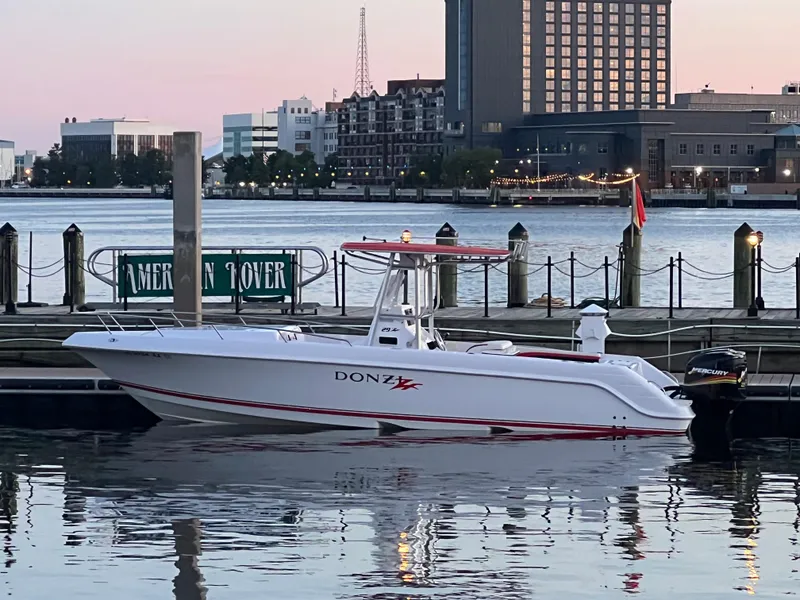 Slide: The Image of 2002 Donzi 29 ZF Cuddy boat docked by waterfront cityscape. - 2