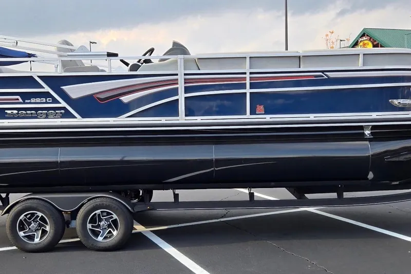 Slide: The Image of 2023 Ranger Reata 223C pontoon boat on trailer in parking lot. - 4