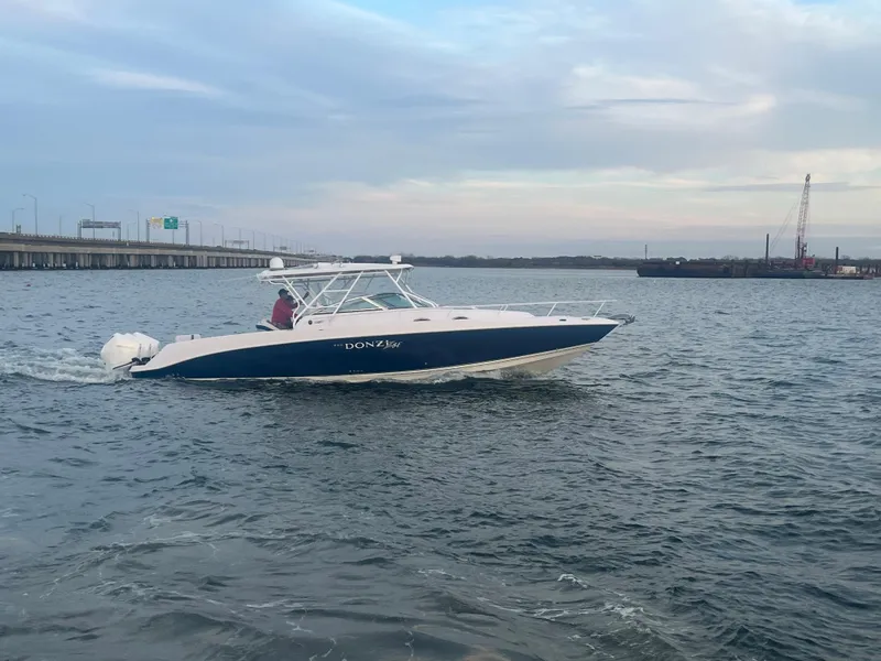 Slide: The Image of 2008 Donzi 38 ZSF boat cruising on open water near a bridge. - 15