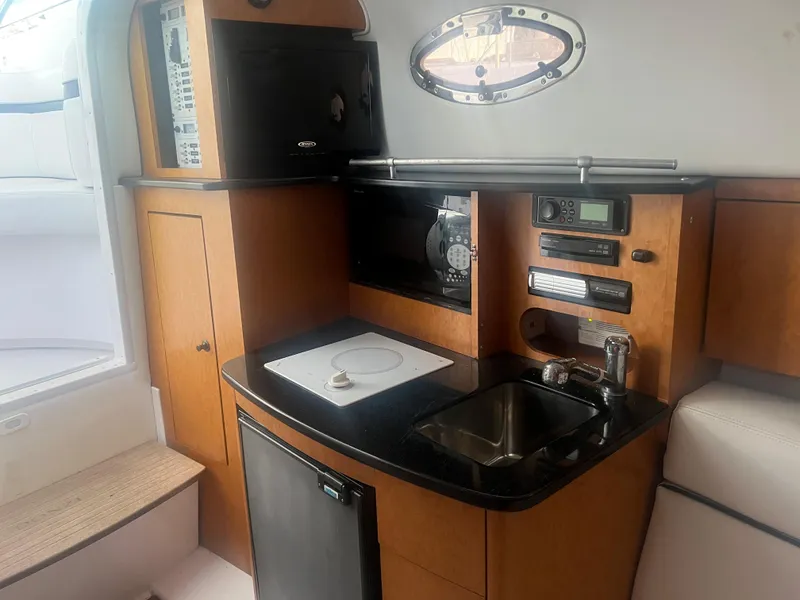 Slide: The Image of 2008 Donzi 38 ZSF boat interior kitchen with sink, stove, microwave, and storage cabinets. - 26