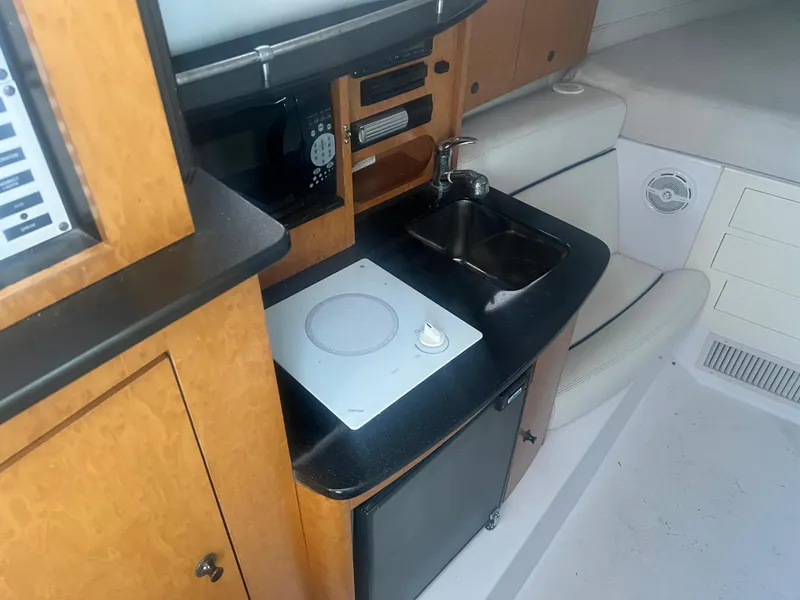 Slide: The Image of 2008 Donzi 38 ZSF boat interior kitchen with stove, sink, microwave, and storage cabinets. - 23