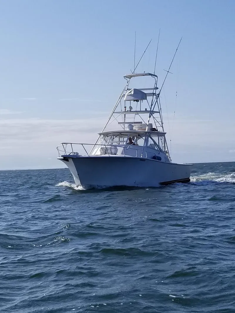 Slide: The Image of 2002 Jersey 36 Express boat cruising on open water under clear skies. - 16