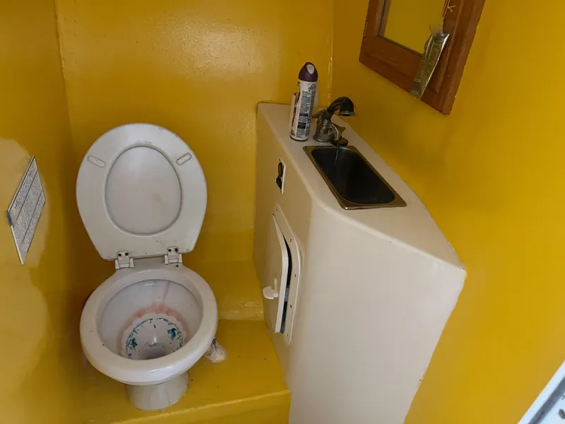 Slide: The Image of Compact yellow bathroom in 2002 Jersey 36 Express boat with toilet, sink, and mirror. - 24
