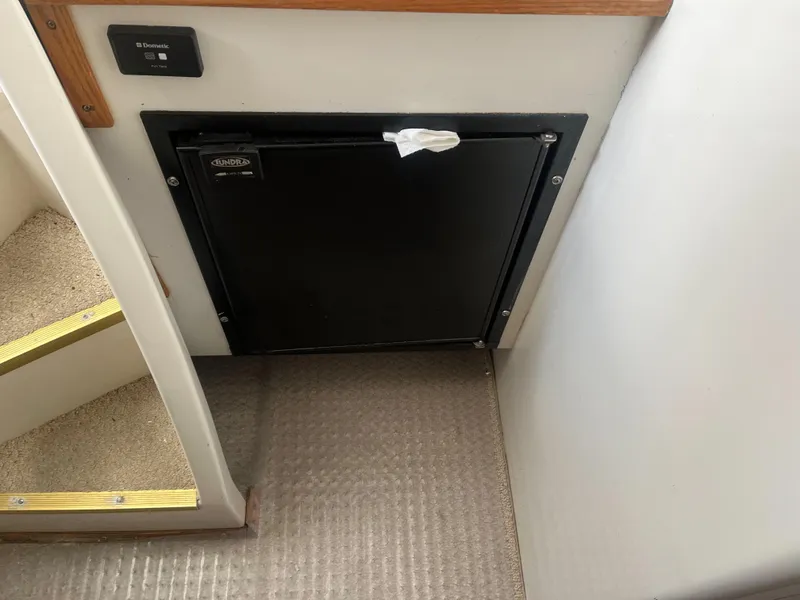 Slide: The Image of 2002 Jersey 36 Express boat interior with a black fridge and carpeted stairs. - 35