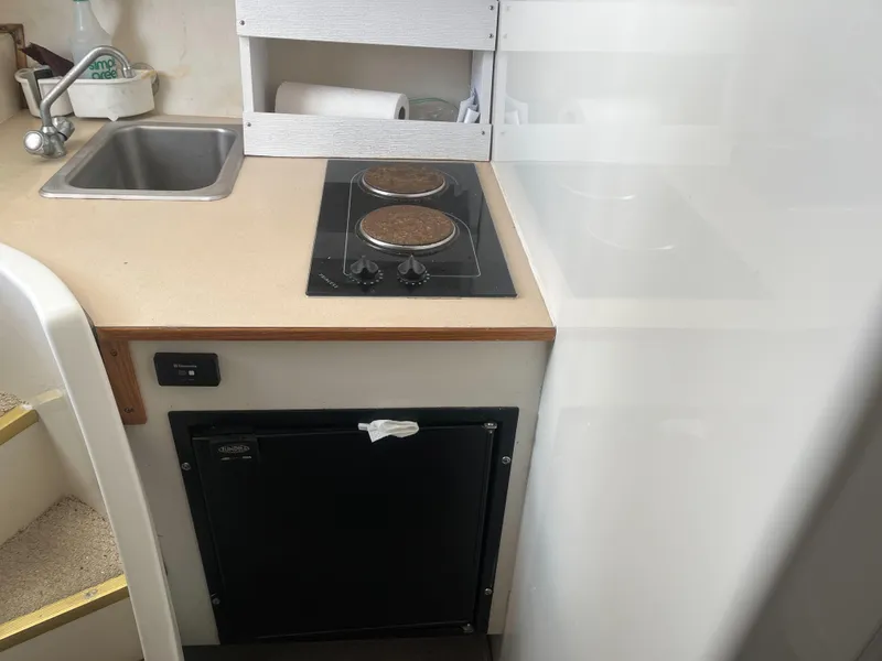 Slide: The Image of Compact kitchen area in a 2002 Jersey 36 Express boat with sink, stove, and mini-fridge. - 36